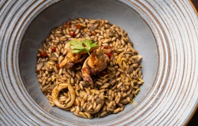 Risoto negro de lula cremoso com arroz arbóreo, tinta de lula, vinho branco e raspas de limão
