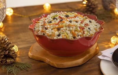Fotografia mostra um arroz à grega servido em uma travessa. O arroz é soltinho e colorido, com pedaços de cenoura, ervilha, pimentão e uvas-passas distribuídos de forma harmoniosa. Fotografia mostra um arroz à grega servido em uma travessa. O arroz é soltinho e colorido, com pedaços de cenoura, ervilha, pimentão e uvas-passas distribuídos de forma harmoniosa.