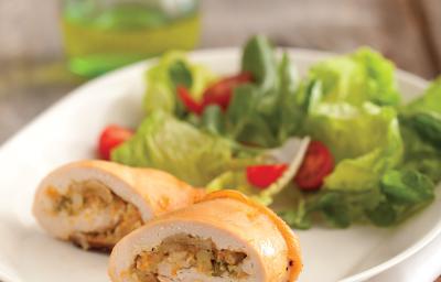 Fotografia em tons de verde em uma bancada de madeira com um prato oval branco com o enroladinho de frango com salada de alface e tomate cereja. Fotografia em tons de verde em uma bancada de madeira com um prato oval branco com o enroladinho de frango com salada de alface e tomate cereja.