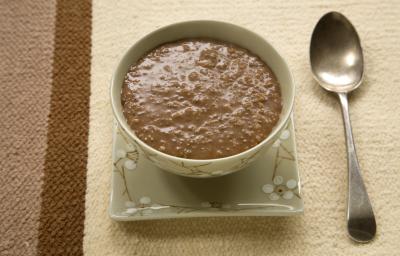 Fotografia de um mingau de chocolate servido em uma tigela, em tons verdes e estampa de flores branca. Fotografia de um mingau de chocolate servido em uma tigela, em tons verdes e estampa de flores branca.