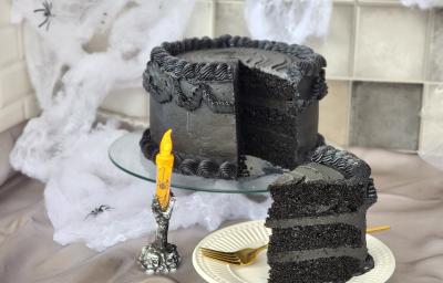 Foto da receita de Bolo de Veludo Preto. Observa-se um bolo alto preto decorado de preto, com uma decoração de Dia das Bruxas. Foto da receita de Bolo de Veludo Preto. Observa-se um bolo alto preto decorado de preto, com uma decoração de Dia das Bruxas.