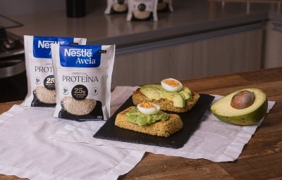 Foto da receita de toast proteico servida em duas porções sobre uma pedra preta em cima de uma mesa de madeira com metade de um avocado ao lado