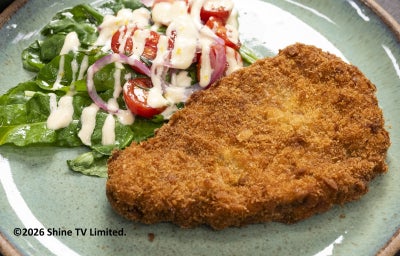 Milanesa uruguaia crocante no prato com salada de rúcula, tomate, cebola e aioli