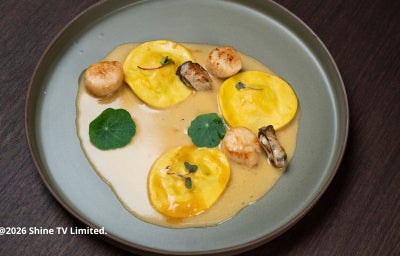Tortelloni de camarão com molho bisque, vieiras grelhadas e flores de capuchinha em prato sofisticado e cheio de sabor.