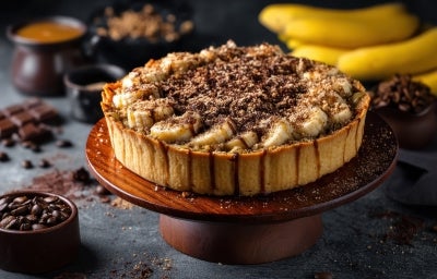 Em cima de uma mesa, banoffee com massa de biscoitos crocante, bananas em rodelas, polvilhado com canela em pó. Em cima de uma mesa, banoffee com massa de biscoitos crocante, bananas em rodelas, polvilhado com canela em pó.