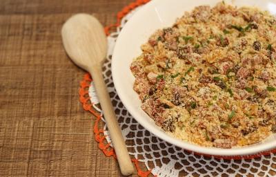 Foto da Receita de Farofa Rica Natalina, fácil e deliciosa, feita com bacon, calabresa, linguiça toscana e farinha de mandioca torrada, servida sobre uma mesa de madeira, com uma colher de pau ao lado