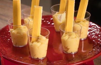 Fotografia em tons de vermelho com um prato vermelho ao centro. Em cima do prato existe uma receita de brigadeiro de maracujá de colher com vários kitkats mysterys espetados como decoração.