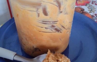 Fotografia de um pote de vidro com doce de leite caseiro com coco sobre um prato raso azul. Na frente do vidro tem uma colher com doce de leite e coco ralado. Fotografia de um pote de vidro com doce de leite caseiro com coco sobre um prato raso azul. Na frente do vidro tem uma colher com doce de leite e coco ralado.
