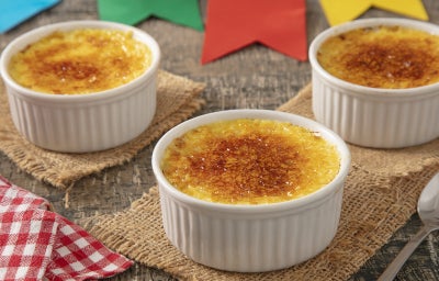 Imagem mostra uma taça de vidro transparente com um creme amarelo claro e superfície dourada tostada