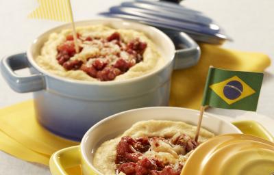 Fotografia em tons de branco, amarelo e azul de uma bancada branca com um paninho amarelo, sobre ele dois recipiente em formato de panelinha, um amarelo e um azul com polenta. Fotografia em tons de branco, amarelo e azul de uma bancada branca com um paninho amarelo, sobre ele dois recipiente em formato de panelinha, um amarelo e um azul com polenta.