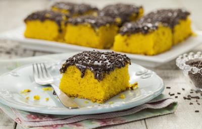 Foto de um pedaço de bolo de cenoura com cobertura de brigadeiro em um prato branco com um garfo do lado Foto de um pedaço de bolo de cenoura com cobertura de brigadeiro em um prato branco com um garfo do lado