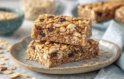 imagem mostra barrinhas de cereal com Fiber Mais® Sem Sabor, aveia, sementes, uvas-passas e amêndoas, cortadas em porções individuais.