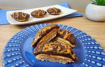 Fotografia em tons de azul em uma bancada de madeira e um prato azul redondo com tortinhas de caramelo salgado com chocolate e aveia em cima dele. Fotografia em tons de azul em uma bancada de madeira e um prato azul redondo com tortinhas de caramelo salgado com chocolate e aveia em cima dele.