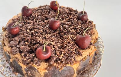 Fotografia em tons de branco com um bolo de Cuca de maçã verde ao centro enfeitada com cerejas