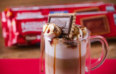 Fotografia em tons de vermelho com uma caneca de vidro ao centro. Dentro da caneca existe uma receita de café com leite finalizada com marshmallow e Choco Biscuit NESTLÉ Fotografia em tons de vermelho com uma caneca de vidro ao centro. Dentro da caneca existe uma receita de café com leite finalizada com marshmallow e Choco Biscuit NESTLÉ