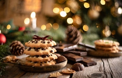 Em cima de uma mesa, em cima de um prato, biscoitos com gotas de chocolate perfilado um em cima de outro, decorado com um laço marrom. Em cima de uma mesa, em cima de um prato, biscoitos com gotas de chocolate perfilado um em cima de outro, decorado com um laço marrom.