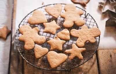 Em cima de uma mesa, grade com biscoitos em formato de coração, estrelas e bonecos de gengibre.