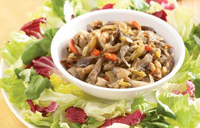 Fotografia em tons de verde e vermelho em uma bancada de madeira com um jogo americano amarelo. Ao centro, um prato branco raso redondo grande com salada de alface e abobrinha. E ao centro, um potinho com o antepasto de berinjela. Fotografia em tons de verde e vermelho em uma bancada de madeira com um jogo americano amarelo. Ao centro, um prato branco raso redondo grande com salada de alface e abobrinha. E ao centro, um potinho com o antepasto de berinjela.