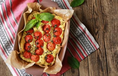 Fotografia em tons de amarelo com uma focaccia com tomates ao centro Fotografia em tons de amarelo com uma focaccia com tomates ao centro
