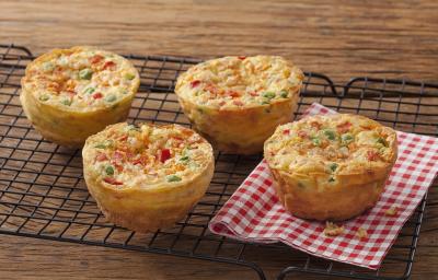 Fotografia em tons de vermelho em uma bancada de madeira com um pano xadrez vermelho com quatro muffins de tapioca com legumes. Fotografia em tons de vermelho em uma bancada de madeira com um pano xadrez vermelho com quatro muffins de tapioca com legumes.