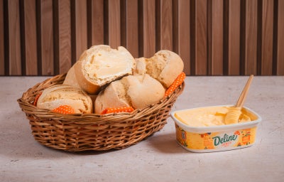 Pãezinhos de milho caseiros em cesta com margarina Deline derretendo em um pão