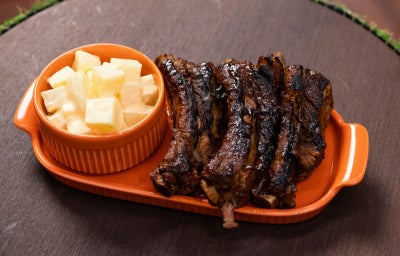 Costelinhas ao barbecue grelhadas com salada de batata cremosa em prato laranja