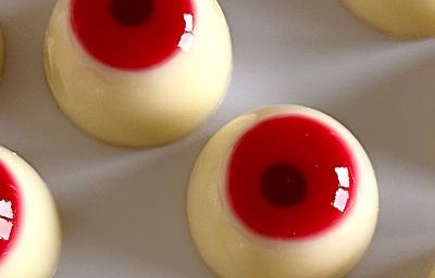 Fotografia em tons claros de varios olhos de gelatina e leite moça para o halloween sobre uma mesa branca. Fotografia em tons claros de varios olhos de gelatina e leite moça para o halloween sobre uma mesa branca.