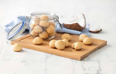Receita em tons de bege e azul de uma bancada branca vista de cima. Contém uma tábua bege com um pote transparente com biscoitinhos dentro e por cima da tábua contém mais biscoitos. Ao fundo um pano azul e uma coco cortado. Receita em tons de bege e azul de uma bancada branca vista de cima. Contém uma tábua bege com um pote transparente com biscoitinhos dentro e por cima da tábua contém mais biscoitos. Ao fundo um pano azul e uma coco cortado.