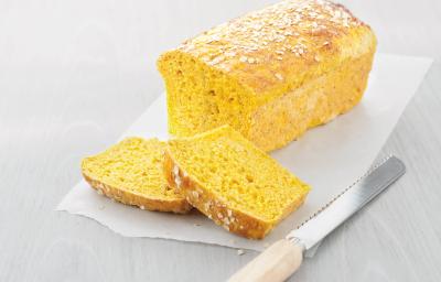 fotografia em tons de branco e amarelo tirada de um pão e duas fatias do mesmo e ao lado uma faca.