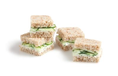 Fotografia em tons de verde em um fundo branco com quatro mini sanduichinhos no pão integral com recheio de pepino. Fotografia em tons de verde em um fundo branco com quatro mini sanduichinhos no pão integral com recheio de pepino.