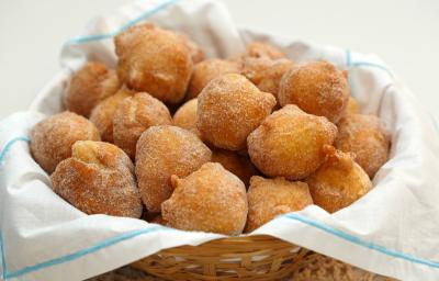 Fotografia em tons de branco de uma  bancada branca com uma cesta, sobre ela um paninho branco com bolinhos de chuvas.