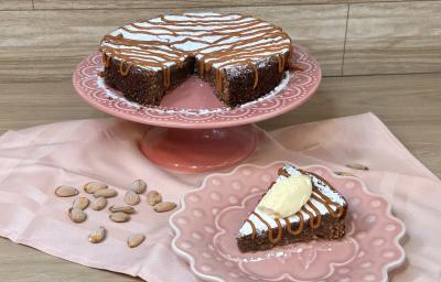 Fotografia em tons de rosa com uma toalha e um prato bailarina ao centro. Em cima do prato existe uma receita de torta italiana com recheio de chocolate e caramelo toffee