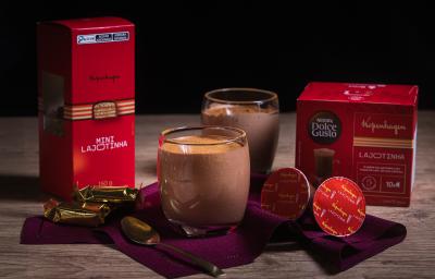Fotografia em tons escuros de dois copos de vidro com uma receita de Mousse Cappuccino Lajotinha com cacau em pó por cima sobre um pano vinho escuro com duas cápsualsa de kopenhagen, uma colher pequena e duas lajotinhas. Fotografia em tons escuros de dois copos de vidro com uma receita de Mousse Cappuccino Lajotinha com cacau em pó por cima sobre um pano vinho escuro com duas cápsualsa de kopenhagen, uma colher pequena e duas lajotinhas.