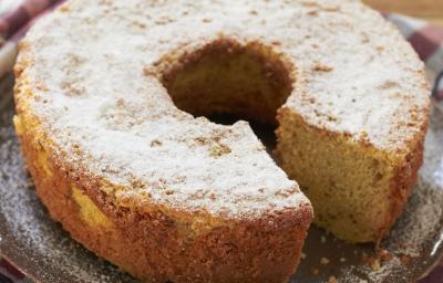 em uma mesa de madeira contém um pano xadrez nos tons vinho e cinza e por cima do pano o bolo de fubá coberto com açúcar de confeiteiro. em uma mesa de madeira contém um pano xadrez nos tons vinho e cinza e por cima do pano o bolo de fubá coberto com açúcar de confeiteiro.