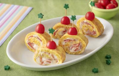 Foto da receita de Enroladinho de Omelete. Observa-se um prato branco com 5 enroladinhos de omelete de pé dispostos. Para prender os enroladinhos, tem um palitinho com estrela verde na ponta espetando uma metade de tomate-cereja. Foto da receita de Enroladinho de Omelete. Observa-se um prato branco com 5 enroladinhos de omelete de pé dispostos. Para prender os enroladinhos, tem um palitinho com estrela verde na ponta espetando uma metade de tomate-cereja.
