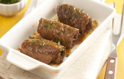 em uma mesa amarela. contém panos brancos e acima um recipiente que comporta os enrolados de carne. em uma mesa amarela. contém panos brancos e acima um recipiente que comporta os enrolados de carne.