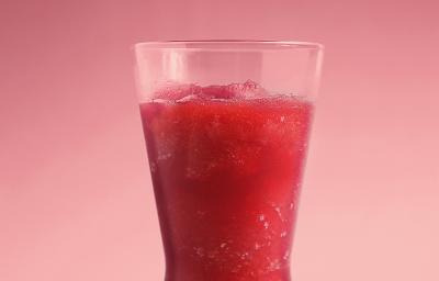 Fotografia em tons de vermelho e rosa de uma bancada rosa sobre ela um copo de vidro com suco de melancia. Fotografia em tons de vermelho e rosa de uma bancada rosa sobre ela um copo de vidro com suco de melancia.