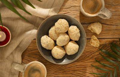 Foto da receita de pão de queijo de aveia servida em diversas porções em um bowl de cerâmica cinza em cima de uma mesa de madeira com um pano de linho ao lado Foto da receita de pão de queijo de aveia servida em diversas porções em um bowl de cerâmica cinza em cima de uma mesa de madeira com um pano de linho ao lado
