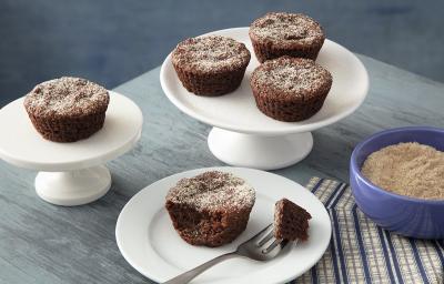 Foto em tons de cinza da receita de bolo de chocolate de farinha láctea aveia servida em diversas porções, três em uma base de porcelana branca e uma com uma garfada servida em um prato de mesmo material. Tudo isso sobre uma mesa cinza Foto em tons de cinza da receita de bolo de chocolate de farinha láctea aveia servida em diversas porções, três em uma base de porcelana branca e uma com uma garfada servida em um prato de mesmo material. Tudo isso sobre uma mesa cinza
