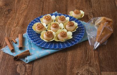 Foto da receita de brigadeiro de churros da arícia, servidos em forminhas amarelas, sobre um prato azul, numa bancada de madeira decorada com um pano azul, alguns paus de canela e um saco de confeitar com doce de leite dentro Foto da receita de brigadeiro de churros da arícia, servidos em forminhas amarelas, sobre um prato azul, numa bancada de madeira decorada com um pano azul, alguns paus de canela e um saco de confeitar com doce de leite dentro