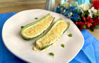 Fotografia em tons de azul com um prato branco com centro. Dentro do prato existe uma receita de abobrinha recheada com creme de ASCENDA e cream cheese Fotografia em tons de azul com um prato branco com centro. Dentro do prato existe uma receita de abobrinha recheada com creme de ASCENDA e cream cheese