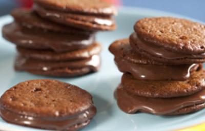 fotografia em tons de marrom, branco e azul tirada de uma bailarina branca com Whoopies Nescau por cima com recheio de brigadeiro fotografia em tons de marrom, branco e azul tirada de uma bailarina branca com Whoopies Nescau por cima com recheio de brigadeiro