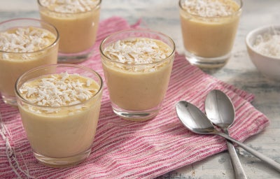 Imagem mostra uma pequena taça transparente com um creme branco dentro e pedaços de coco ralado
