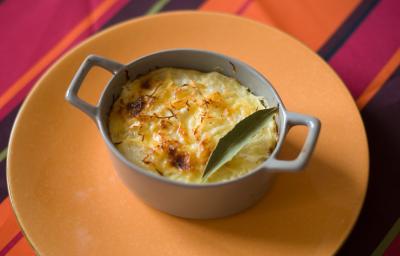 Fotografia de um recipiente pequeno que foi ao forno com uma receita de chuchu recheado com creme de milho e frango. A receita foi gratinada e tem uma folha de louro por cima. Fotografia de um recipiente pequeno que foi ao forno com uma receita de chuchu recheado com creme de milho e frango. A receita foi gratinada e tem uma folha de louro por cima.