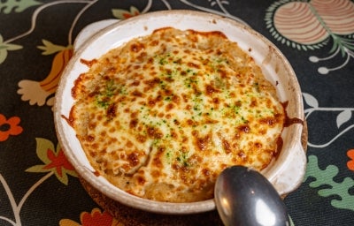 Em uma mesa, prato redondo com queijo gratinado.