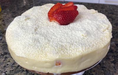 Fotografia em tons de cinza com um bolo de cobertura branca ao centro. Por cima da cobertura existe um polvilhado de Leite NINHO em pó e fatias de morango Fotografia em tons de cinza com um bolo de cobertura branca ao centro. Por cima da cobertura existe um polvilhado de Leite NINHO em pó e fatias de morango