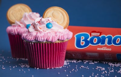 imagem mostra vários bolinhos decorados com chantilly em tons de rosa com biscoitos