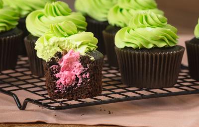 Imagem de cupcakes de chocolate com cobertura verde e recheio rosa.