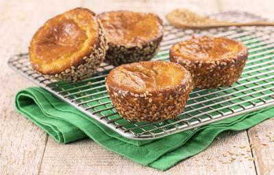 Foto da receita de Muffin Funcional. Observa-se quatro muffins desenformados dispostos sobre uma grade, que está em cima de um guardanapo verde. Atrás, uma pequena colher de madeira.