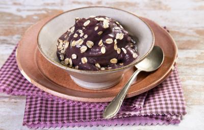 Fotografia em tons de roxo em uma bancada de madeira com um pano xadrez rosa e roxo, um prato raso rosa, um bowl fundo com o açaí dentro dele. Fotografia em tons de roxo em uma bancada de madeira com um pano xadrez rosa e roxo, um prato raso rosa, um bowl fundo com o açaí dentro dele.